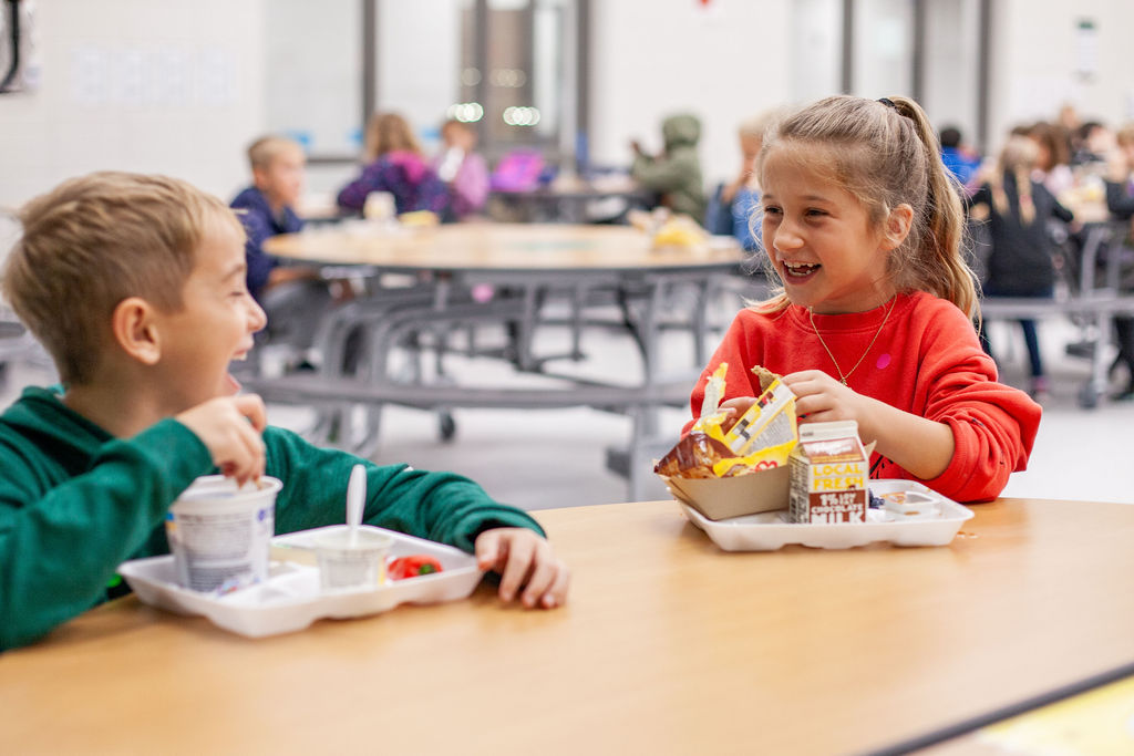 Two elementary students laughing and enjoying lunch