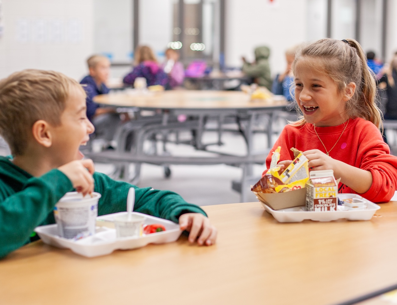 two kids eating lunch together laughing