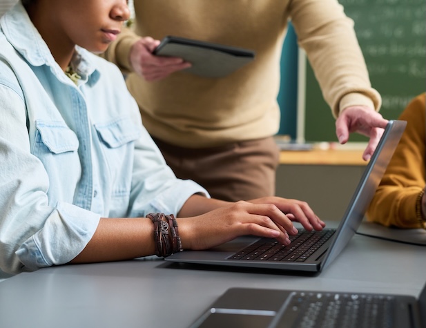 teacher helping student do something on her computer