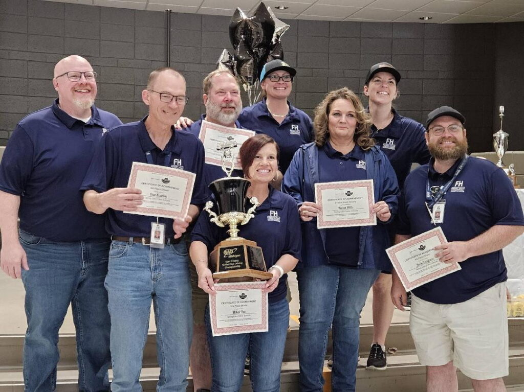 Bus drivers posing with their trophies and certificates after winning the championship
