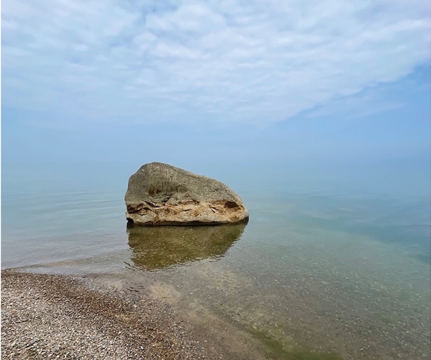 a photo of a big rock in front of the ocean