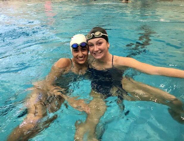 two female swimmers smiling for a photo while swimming