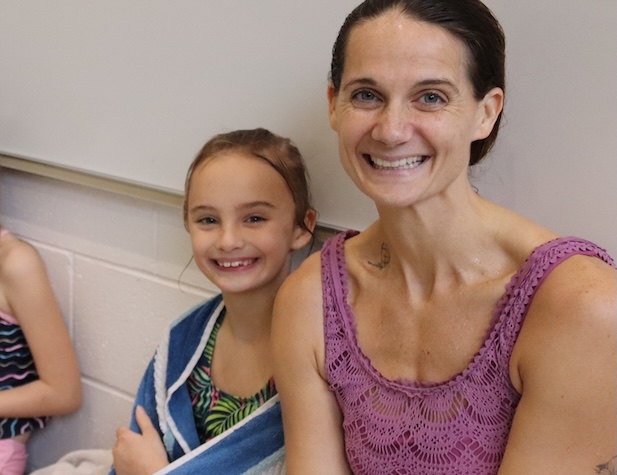 mom and daughter smiling and sitting by the pool in the aquatics centers