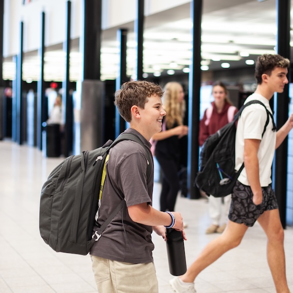 student with a backpack walking to his locker