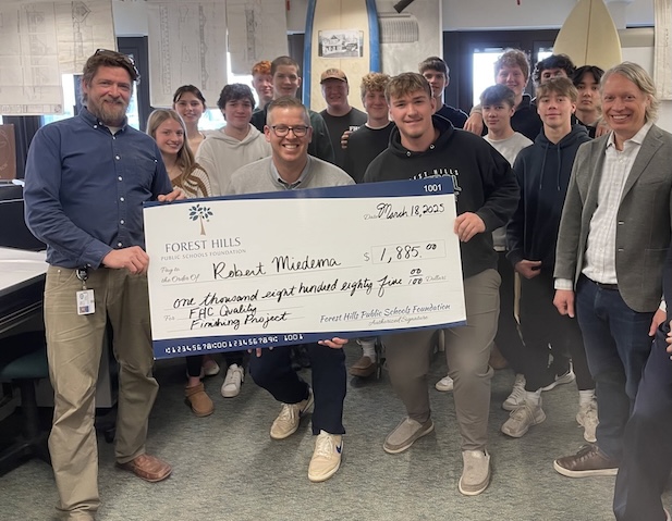 students and staff posing with a giant check for 1885 dollars