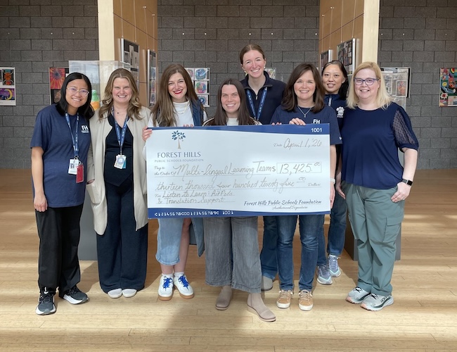 Staff members posing with a giant check in the fine arts center for 13,425 dollars