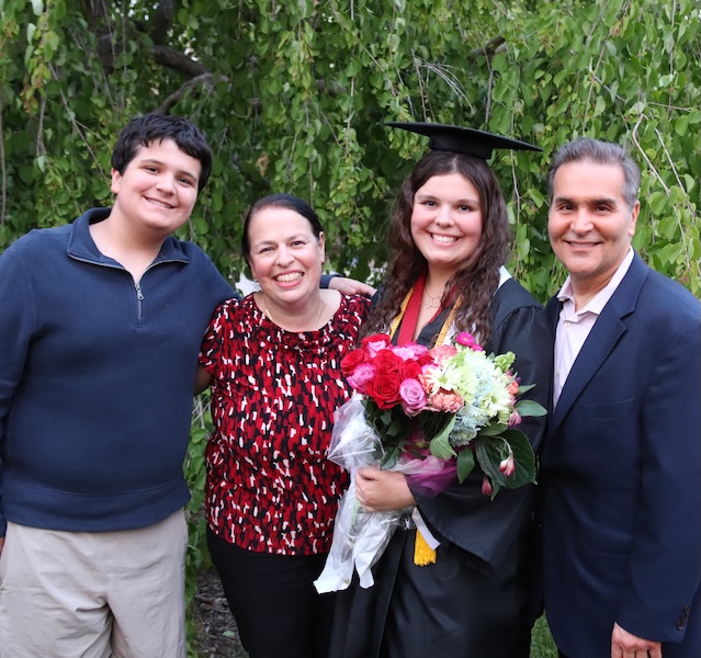 female student posing for a picture with her family at her graduation
