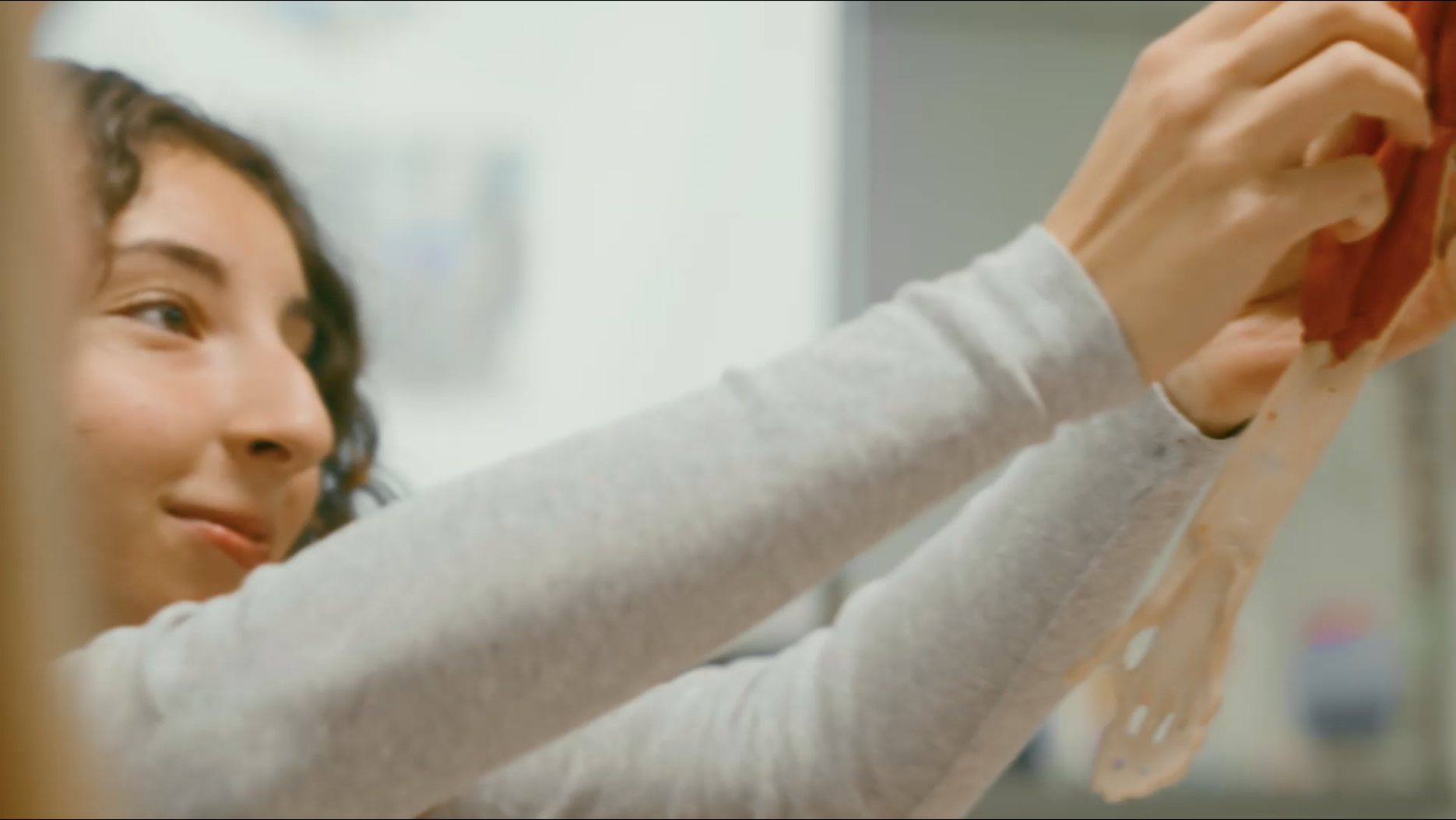 A female student holding something up and smiling