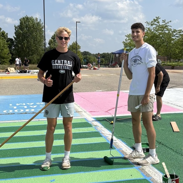 two male students painting their own parking spots